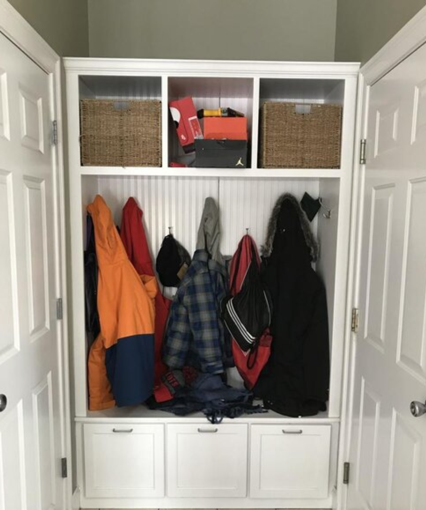 White entryway with coats and storage baskets.